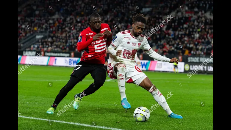 Cầu thủ Rennes đi bóng qua cầu thủ Brest trong trận đấu sôi động. Cầu thủ Rennes đi bóng qua cầu thủ Brest trong trận đấu sôi động.